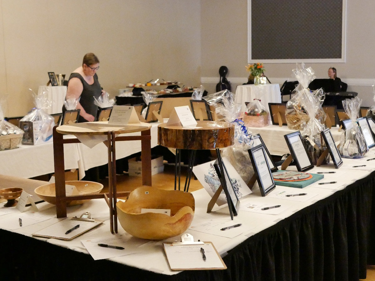 A silent auction table filled with various items including handmade wooden tables